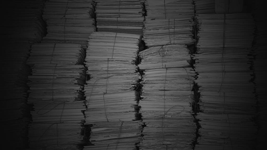 Stacks of bound case papers tied with string, lit from above and falling away into shadow at the edges.