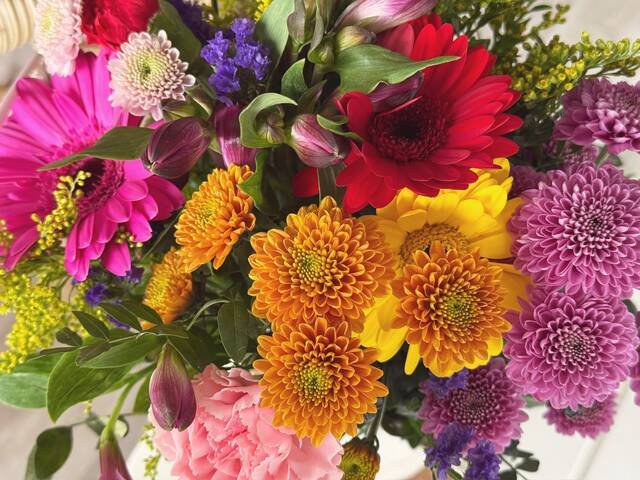 A bright mixed bouquet of gerbera, chrysanthemums and roses in orange, red and pink