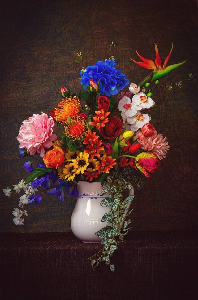 A large statement arrangement of strelitzia, protea, dahlias and roses in a white jug