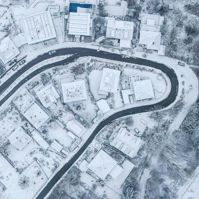 From above: homes and drives along a plowed residential street.