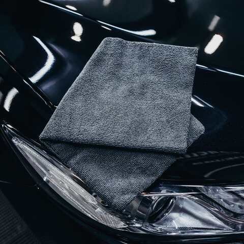 A folded grey microfiber cloth resting on a gloss-black fender above the headlight.