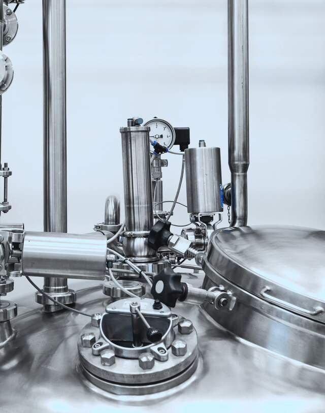 Polished steel valves and pipework on top of a bioreactor.