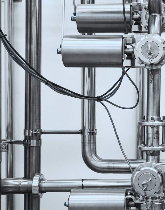 Steel pipework, clamps and actuated valves feeding the bioreactor.