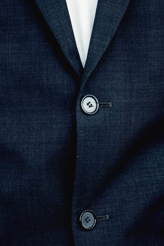 The finished navy coat, buttoned: a soft lapel roll and two hand-worked buttonholes.