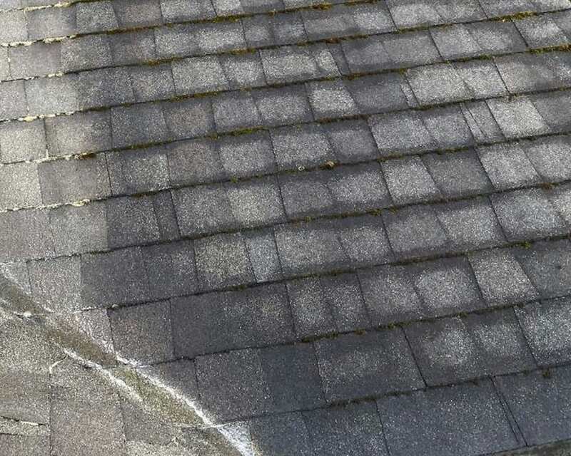 An asphalt shingle roof part-way through a soft wash: the left side washed light, the right still streaked dark with moss in the joints.
