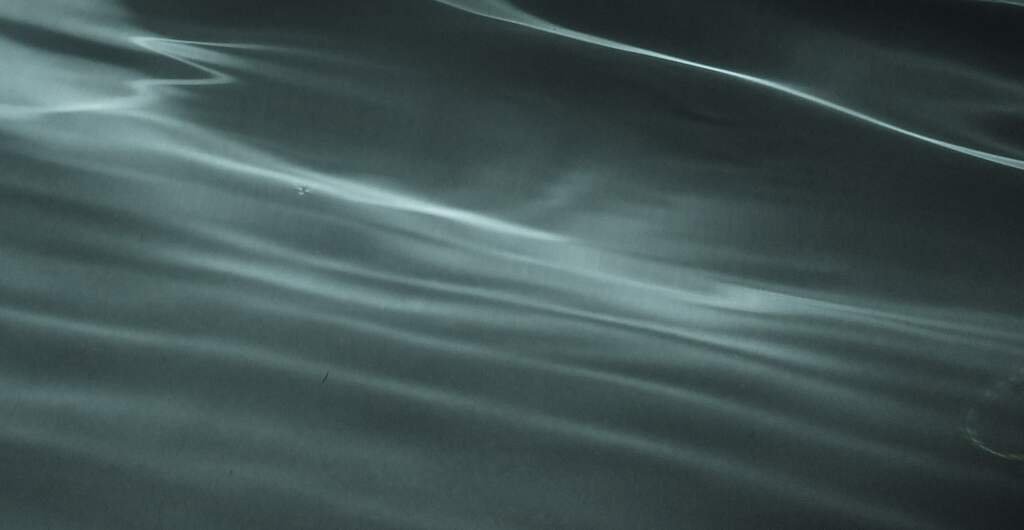 Clear, cold water moving slowly, sea-glass green with light running through it.