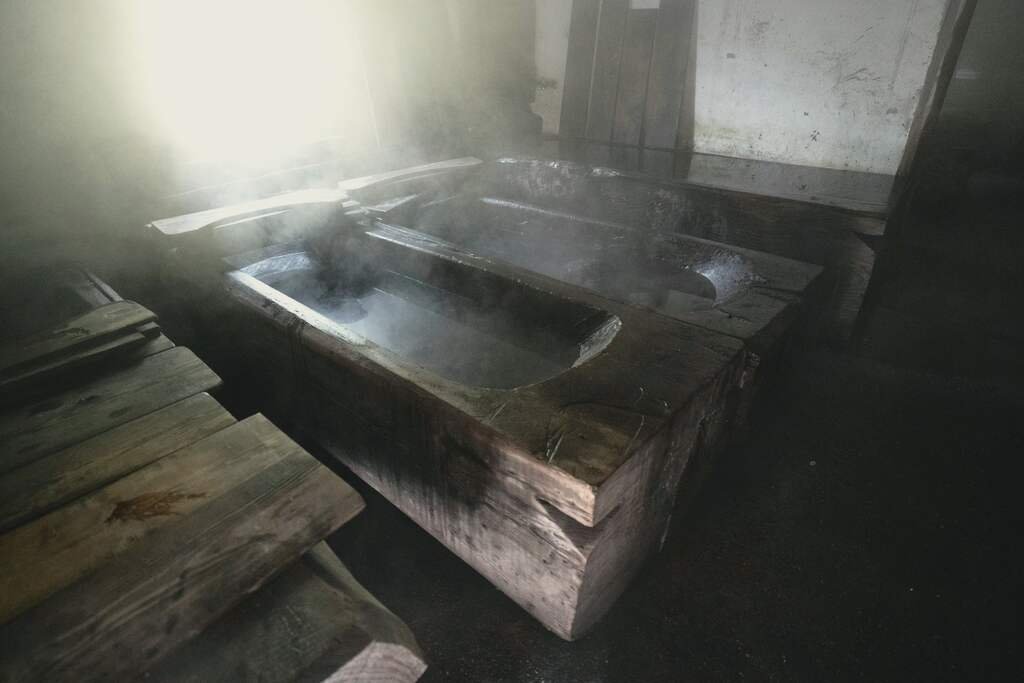 Steam rising off a timber tub in the hot room, caught in a shaft of window light, the air thick and warm.