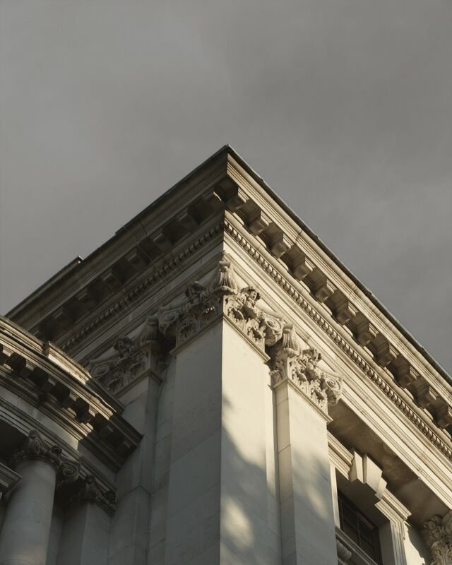 A corner of the restored limestone front: the carved cornice and pilaster capitals in raking light against the sky.