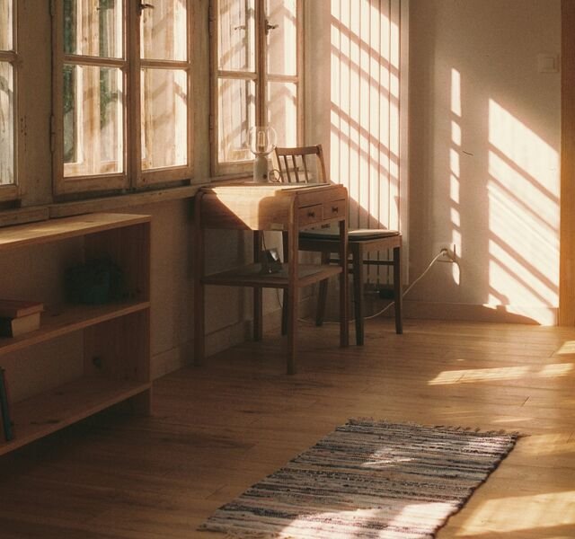 The library of Residence 3.02: a long wall of small-paned windows, a writing desk and stripes of late sun on the plaster.